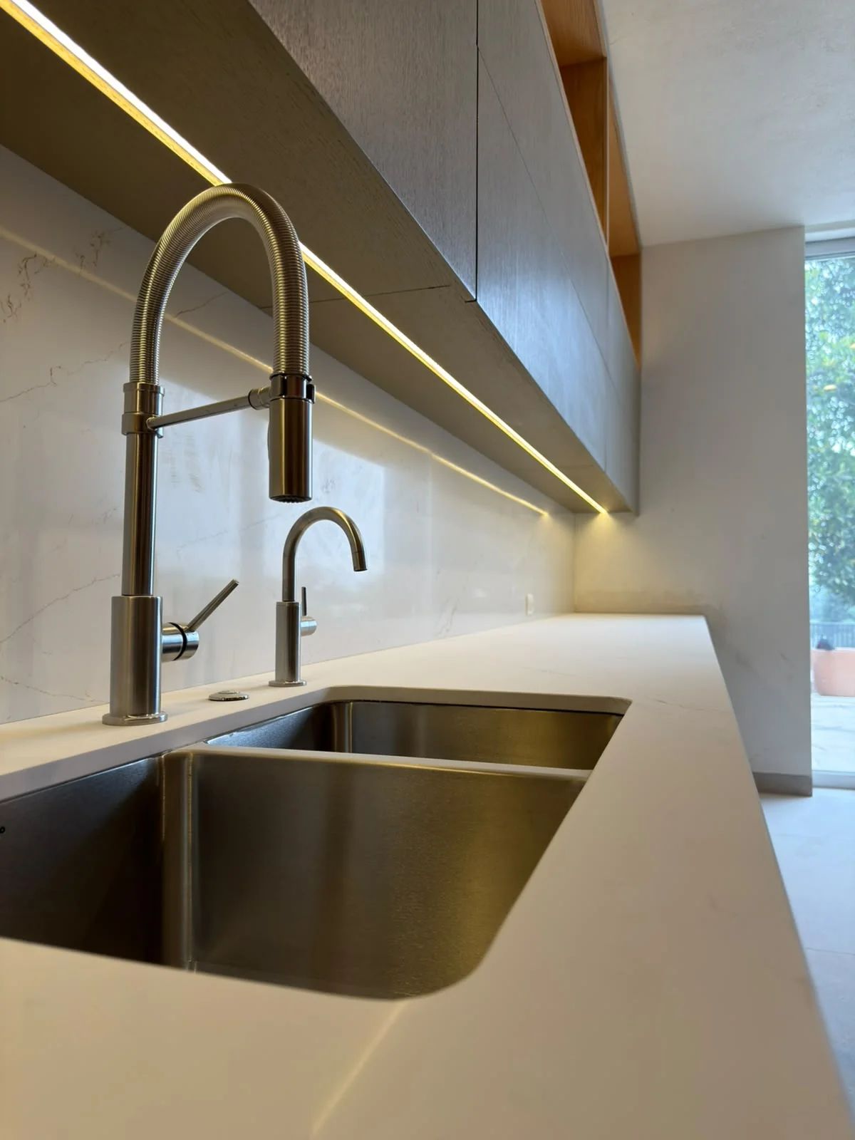 Barra y tarja de cocina iluminadas por una línea de luz debajo del gabinete.