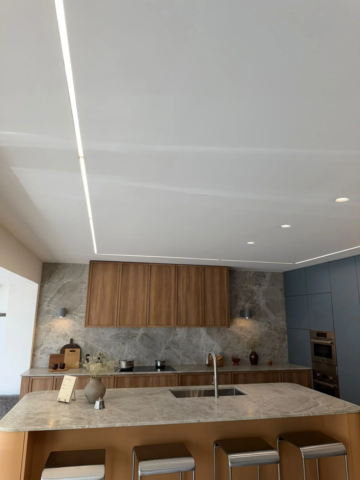Cocina con isla, luminarias empotradas y líneas de luz en el plafón.