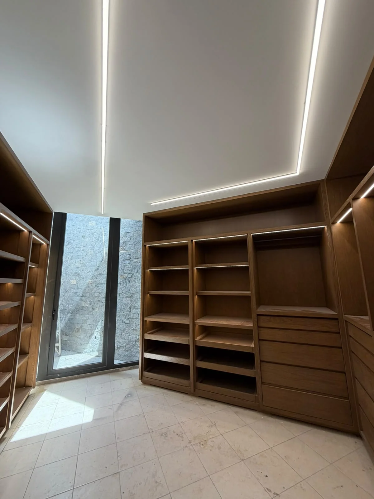 Iluminación lineal formando un contorno en un techo blanco sobre muebles de madera.